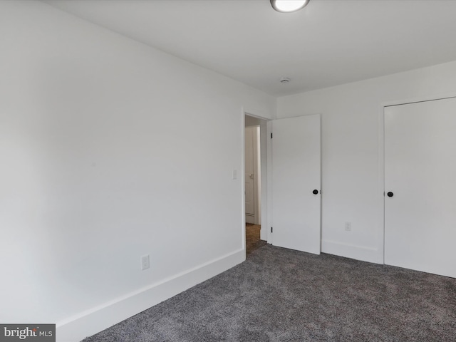 unfurnished bedroom with baseboards and dark carpet