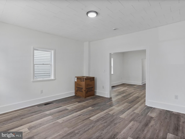 empty room with visible vents, baseboards, and wood finished floors