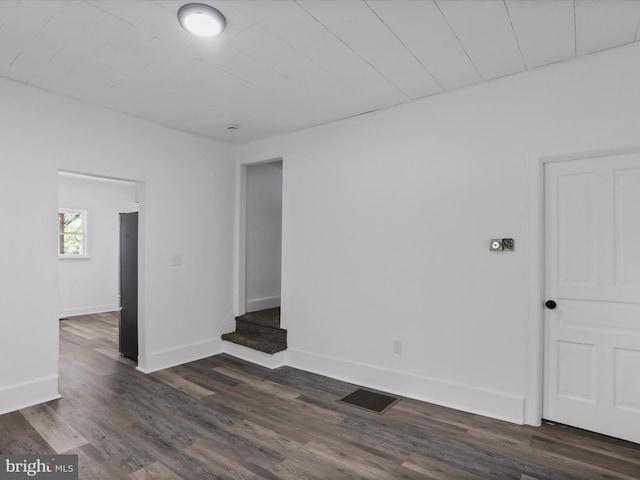 unfurnished room with baseboards, dark wood-type flooring, and visible vents