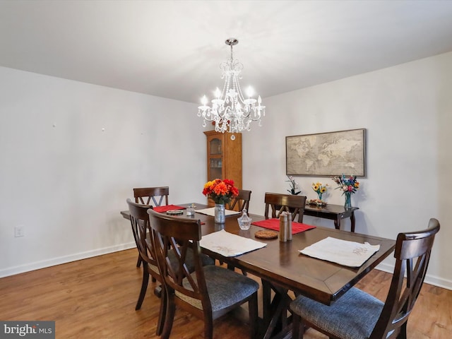 dining area with a notable chandelier, baseboards, and light wood-type flooring