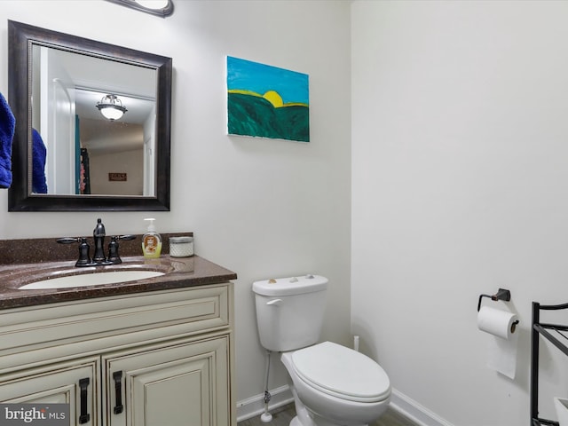 bathroom with toilet, vanity, and baseboards