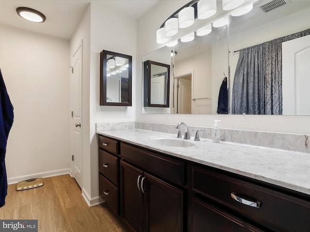 bathroom featuring baseboards, visible vents, wood finished floors, and vanity