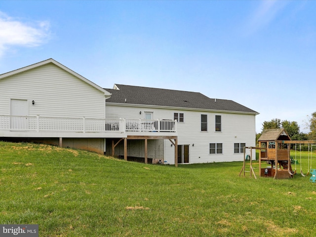 back of house featuring a wooden deck, a playground, and a lawn