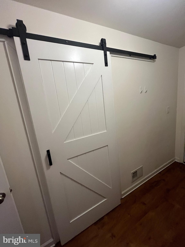 room details with visible vents, wood finished floors, a barn door, and baseboards