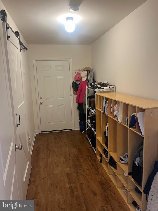 mudroom featuring dark wood-style flooring, a barn door, and baseboards