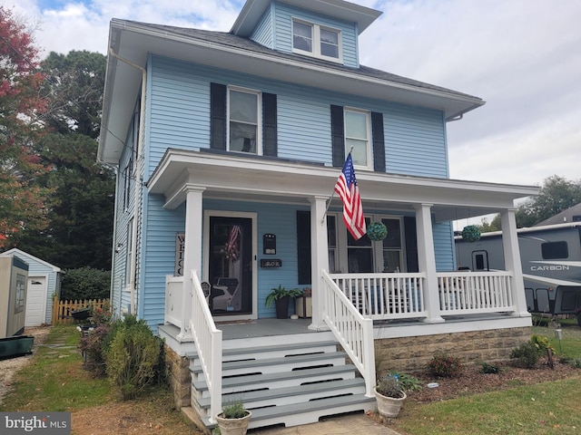 view of front of home with a storage shed and a porch