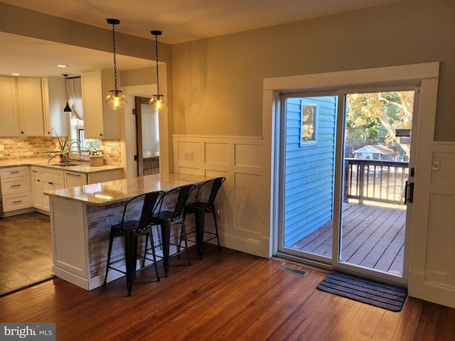 kitchen featuring light stone counters, a kitchen breakfast bar, dark hardwood / wood-style floors, and white cabinets