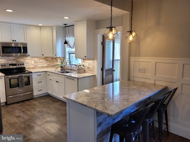 kitchen with appliances with stainless steel finishes, a breakfast bar, white cabinets, and kitchen peninsula