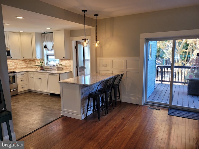 kitchen featuring dark wood-type flooring, white cabinets, stainless steel appliances, and plenty of natural light