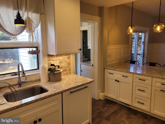 kitchen featuring sink, pendant lighting, white cabinets, light stone counters, and dark hardwood / wood-style floors