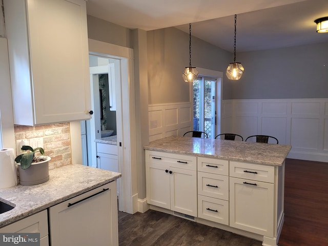 kitchen featuring light stone countertops, decorative light fixtures, dark hardwood / wood-style floors, and white cabinets