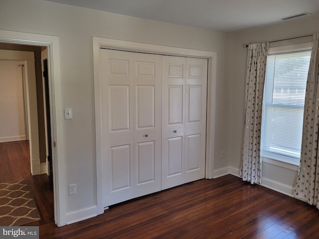 unfurnished bedroom with a closet and dark wood-type flooring