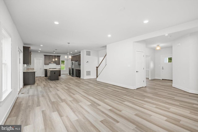 unfurnished living room with plenty of natural light, sink, and light hardwood / wood-style flooring