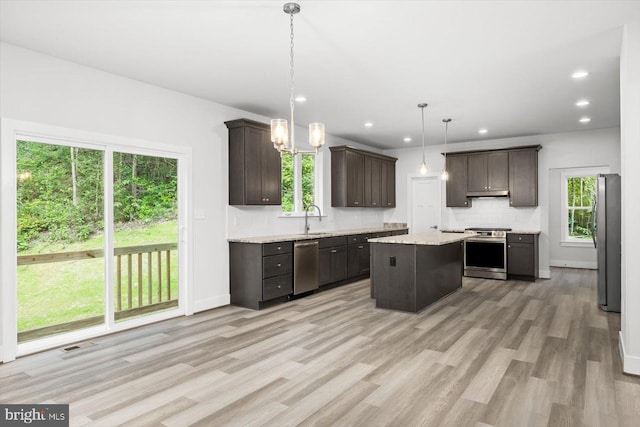 kitchen featuring dark brown cabinetry, a kitchen island, decorative light fixtures, stainless steel appliances, and light wood-type flooring