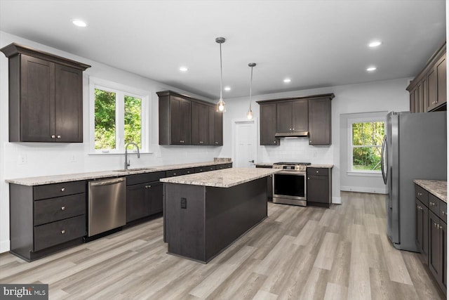 kitchen with sink, a kitchen island, dark brown cabinets, appliances with stainless steel finishes, and light hardwood / wood-style floors