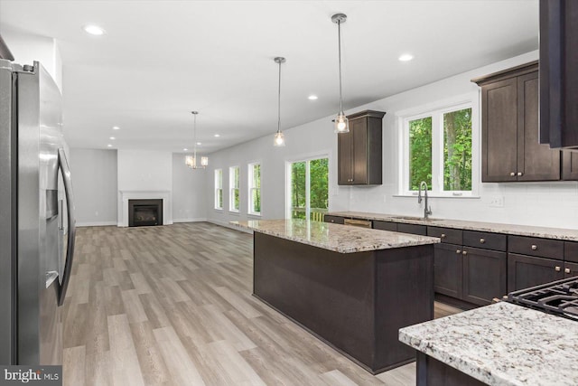 kitchen featuring stainless steel fridge, light hardwood / wood-style flooring, dark brown cabinets, sink, and a center island