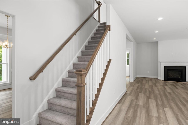 stairs with hardwood / wood-style flooring and a notable chandelier