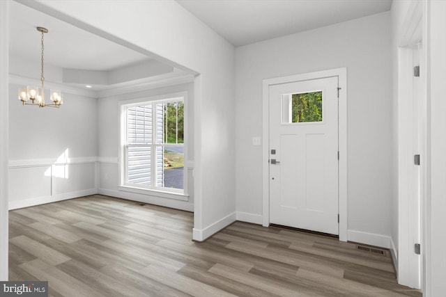 foyer entrance featuring hardwood / wood-style flooring, a notable chandelier, and a tray ceiling