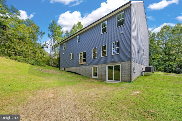 rear view of property with central air condition unit and a lawn