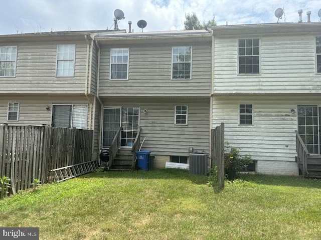 rear view of property featuring cooling unit and a lawn