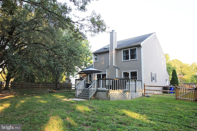 rear view of house featuring a lawn and a deck