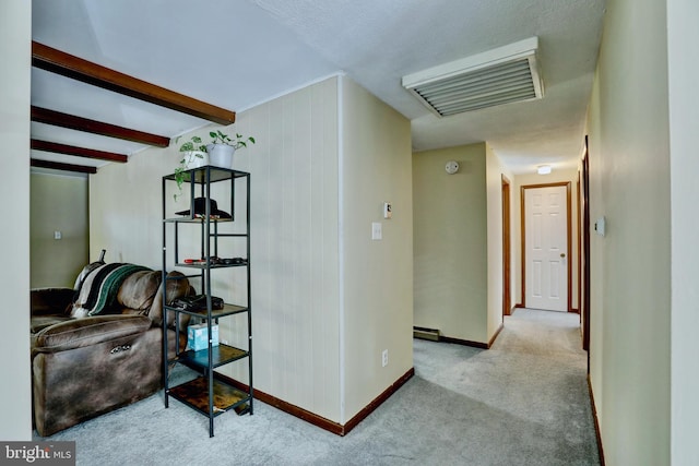 hall with wood walls, beam ceiling, and light colored carpet