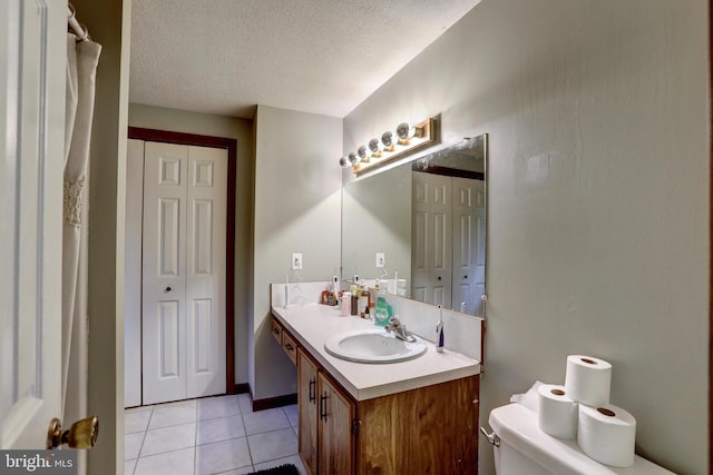 bathroom featuring toilet, a textured ceiling, vanity, and tile patterned floors