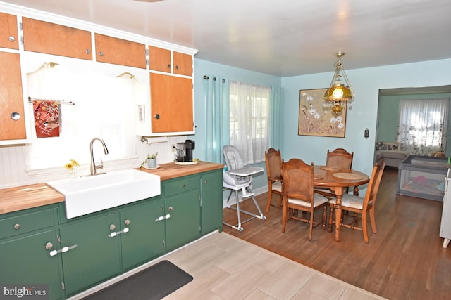 kitchen featuring light hardwood / wood-style flooring, sink, hanging light fixtures, and green cabinetry