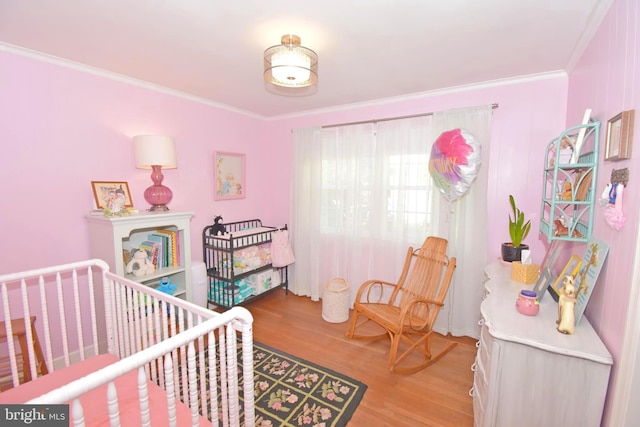 bedroom featuring crown molding, hardwood / wood-style floors, and a nursery area