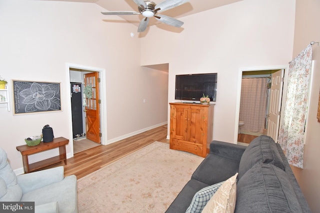 living room with a towering ceiling, light hardwood / wood-style flooring, and ceiling fan