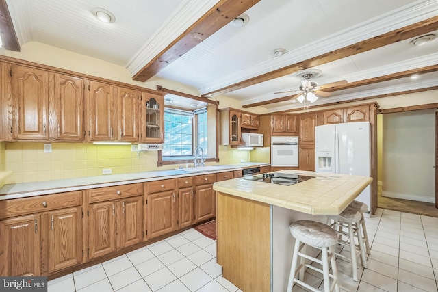 kitchen with white appliances, sink, a kitchen island, beamed ceiling, and light tile patterned floors