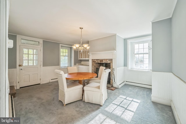 dining space with a baseboard radiator, a notable chandelier, a fireplace, and carpet floors