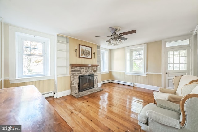 living room featuring ceiling fan, hardwood / wood-style flooring, baseboard heating, and a fireplace