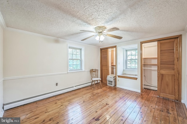 unfurnished bedroom featuring a baseboard radiator, a textured ceiling, multiple windows, and light hardwood / wood-style floors