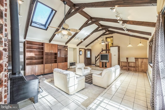 unfurnished living room featuring beamed ceiling, wooden walls, a wood stove, and plenty of natural light