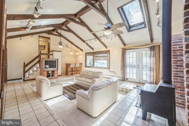 tiled living room with baseboard heating, lofted ceiling with skylight, french doors, and rail lighting