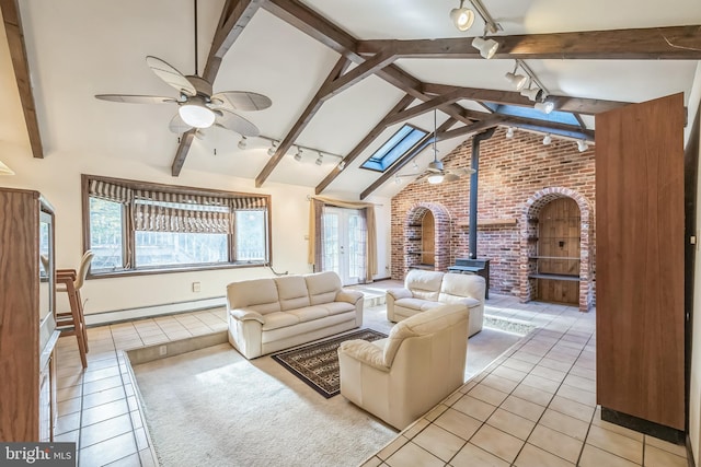 sunroom with track lighting, ceiling fan, vaulted ceiling with skylight, a wood stove, and baseboard heating