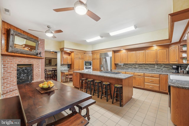 kitchen featuring a kitchen breakfast bar, backsplash, dark stone counters, stainless steel appliances, and a kitchen island