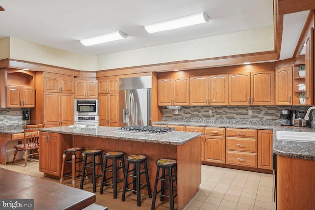 kitchen featuring a breakfast bar, backsplash, sink, a kitchen island, and stainless steel appliances