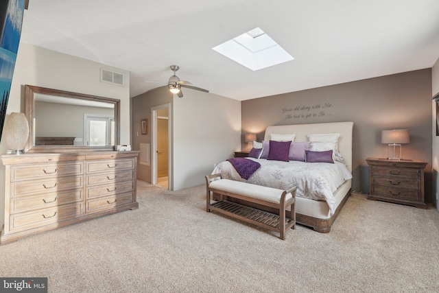 bedroom with a skylight, ceiling fan, ensuite bathroom, and light carpet