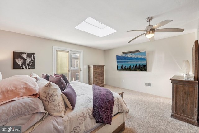 carpeted bedroom featuring ceiling fan, access to outside, and a skylight