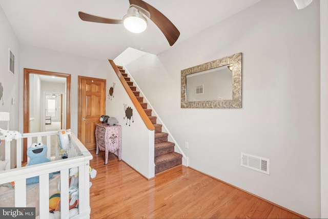 stairway featuring ceiling fan and hardwood / wood-style floors