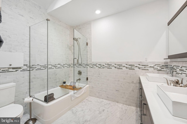 full bathroom featuring vanity, enclosed tub / shower combo, tile walls, and toilet