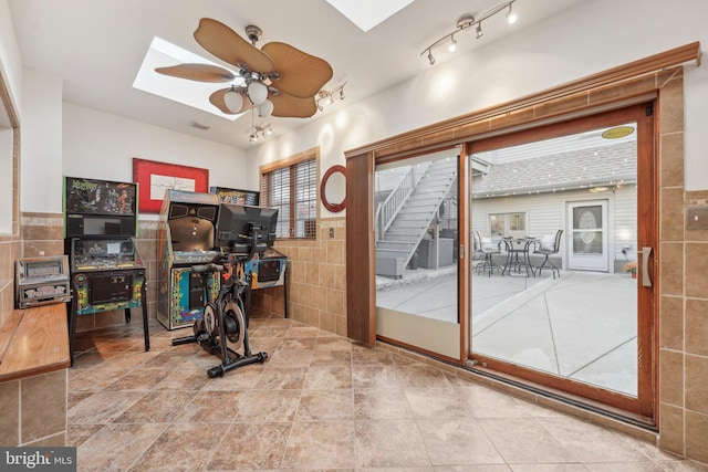 workout area with tile patterned flooring, a skylight, tile walls, and ceiling fan