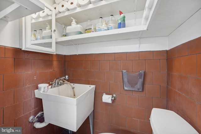 bathroom featuring toilet, sink, and tile walls