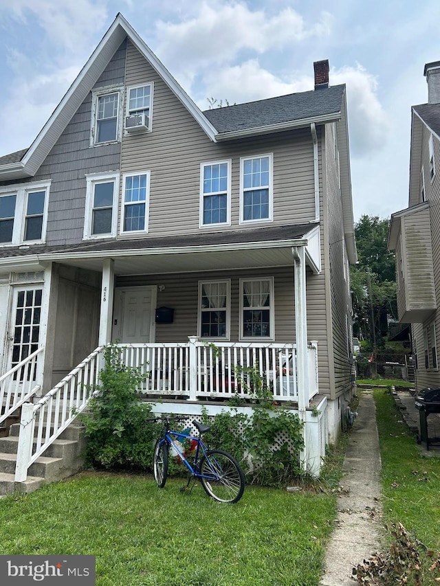 view of front of house with a front yard, cooling unit, and a porch