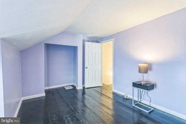 additional living space with vaulted ceiling and dark hardwood / wood-style flooring