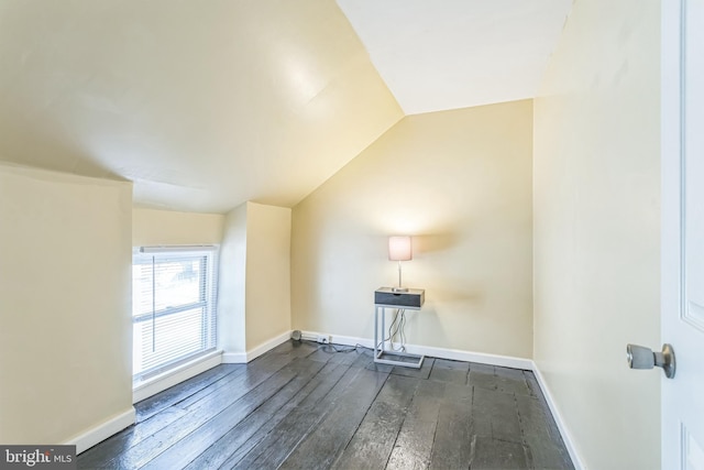 bonus room with dark wood-type flooring and vaulted ceiling