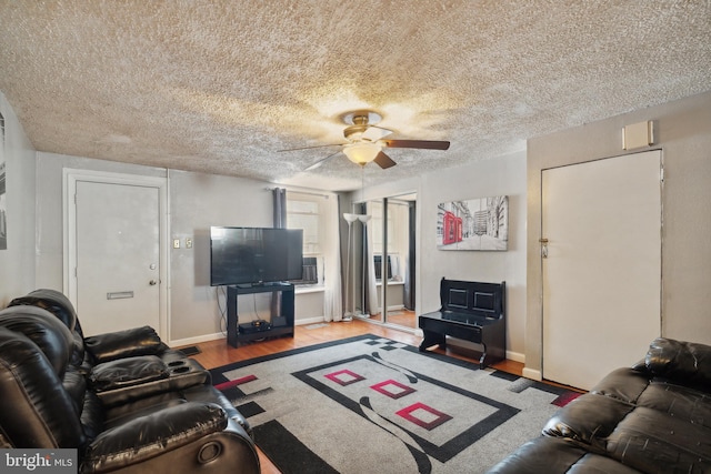 living room featuring ceiling fan, wood-type flooring, and a textured ceiling