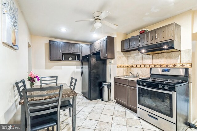 kitchen with ceiling fan, gas range, decorative backsplash, light tile patterned floors, and black refrigerator